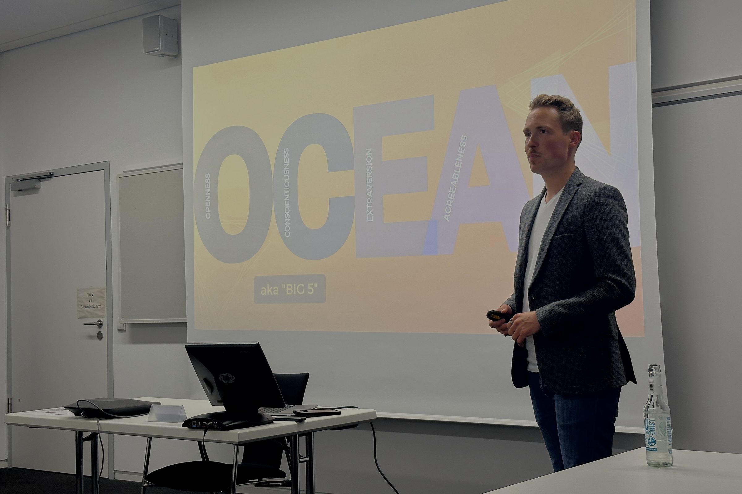 Christoph hält einen Vortrag vor einer Folie zum OCEAN-Persönlichkeitsmodell, auch Big Five genannt