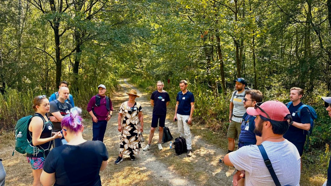 Unternehmer stehen im Kreis auf einem Waldweg und sprechen miteinander
