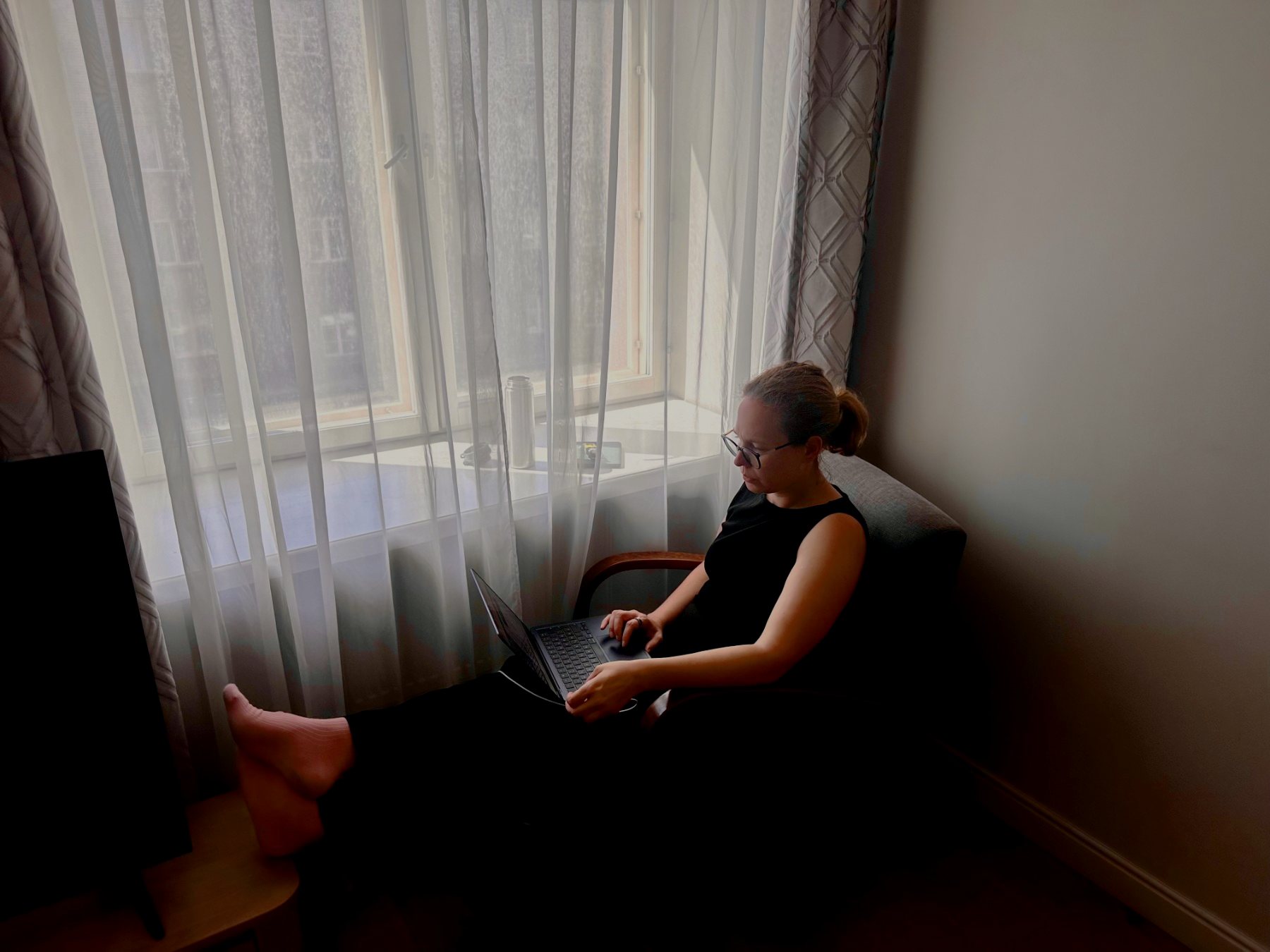 Katharina arbeitet entspannt im Sessel am Fenster am Laptop