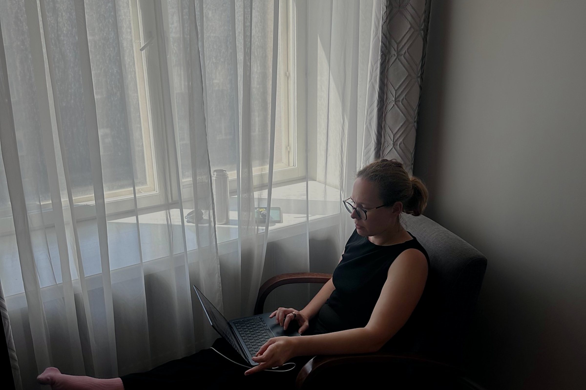 Katharina arbeitet konzentriert am Laptop am Fenster